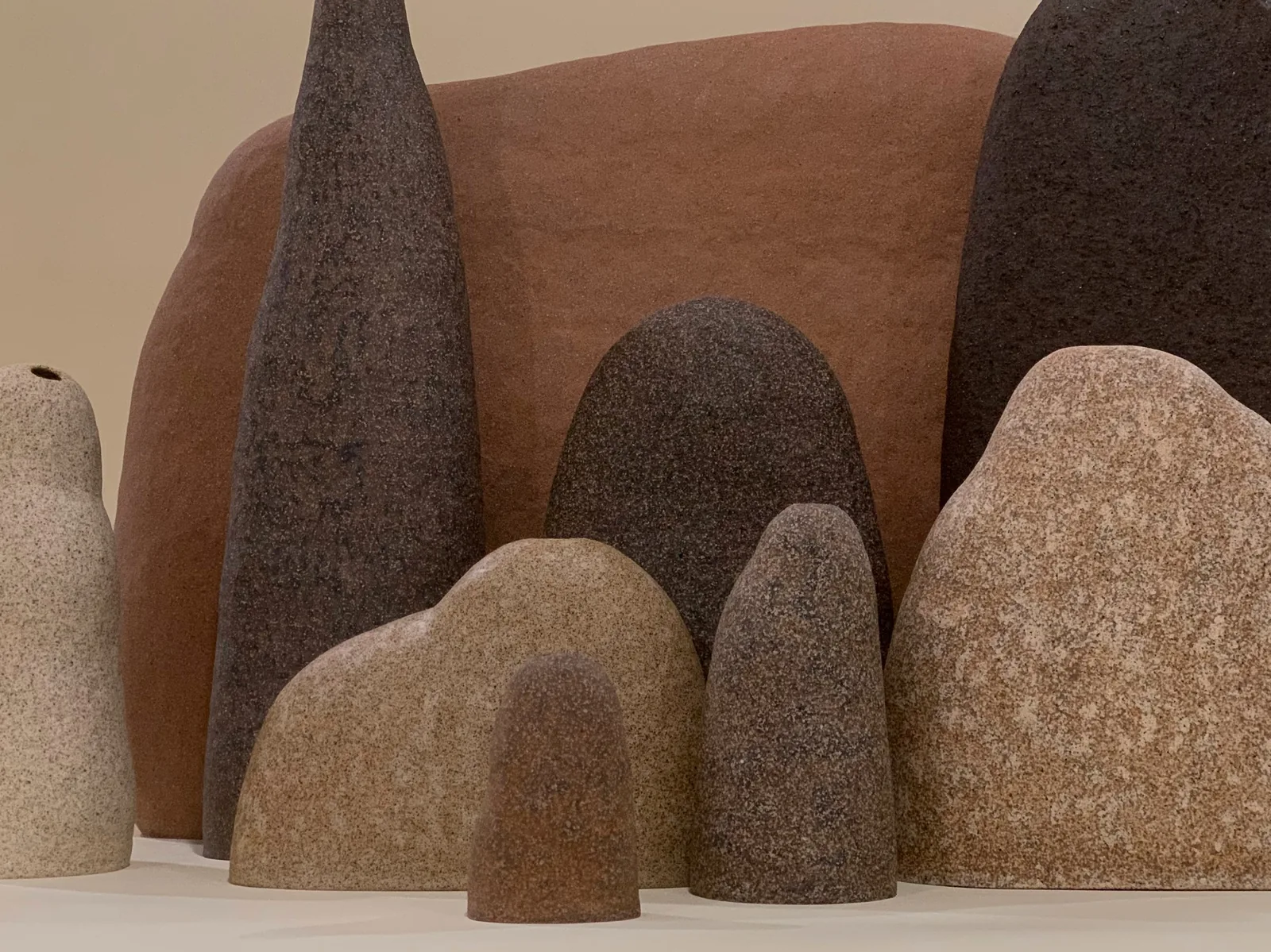 A group of sand-textured ceramic vessels in earth tones